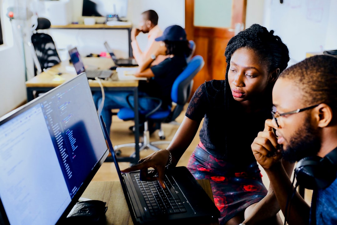 Mentor and junior employee working together at a laptop in a modern office